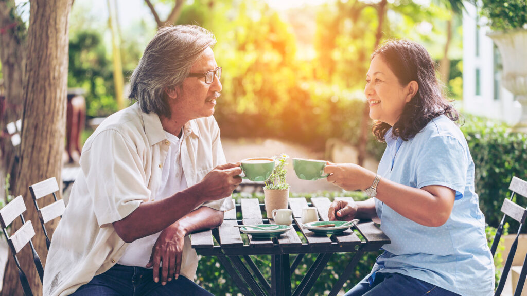 two seniors drinking coffee outside at cafe