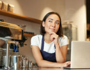 barista with laptop looking curious and thinking