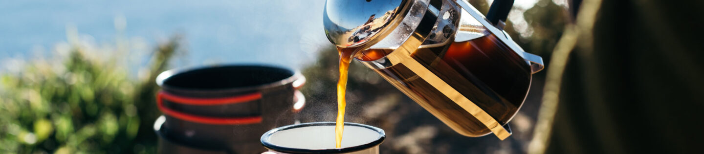 brewed french press pouring into mug in front of coastal horizon