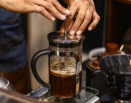 french press brewing with hands pushing plunger