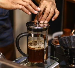 french press brewing with hands pushing plunger