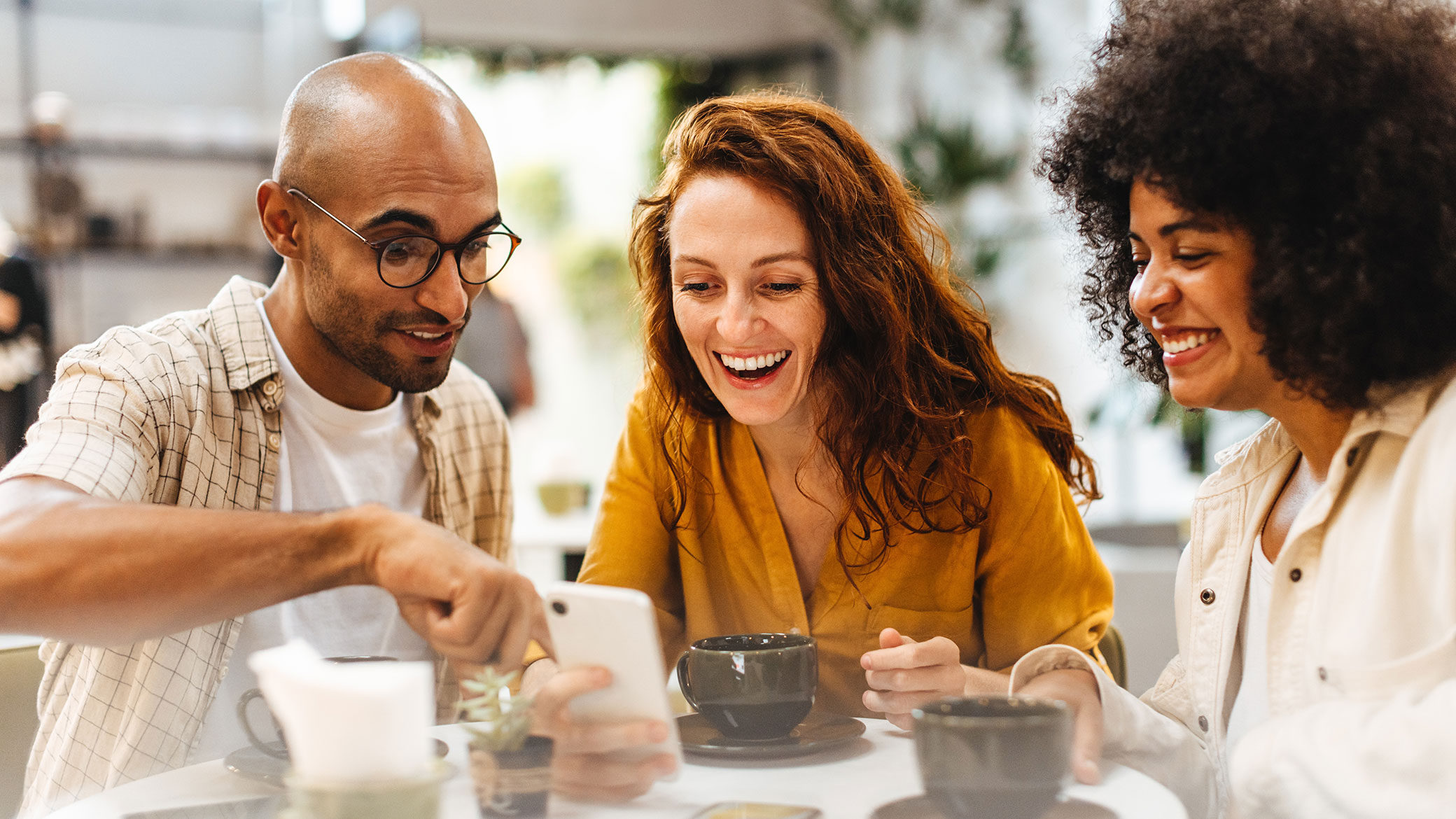 friends sharing coffee and showing info on a phone