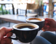 hands clicking two coffee mugs