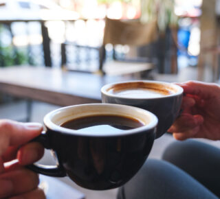 hands clicking two coffee mugs