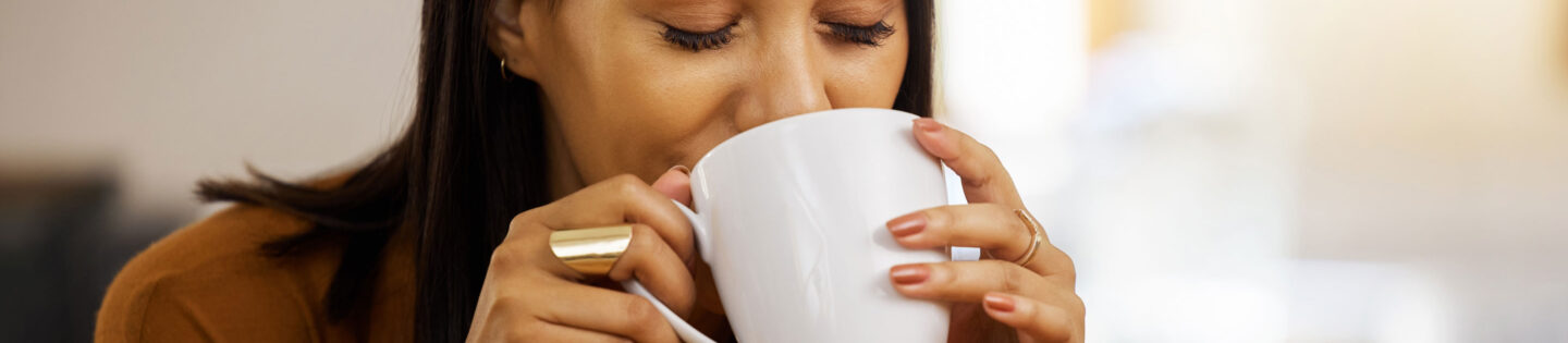 woman drinks from coffee mug with eyes closed