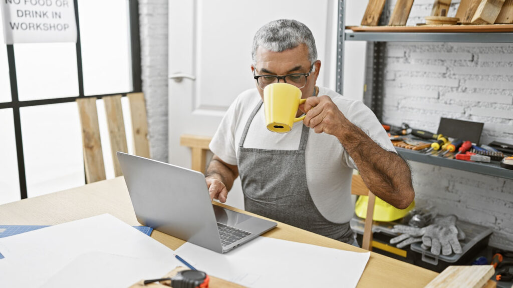 mature man sips coffee in workshop