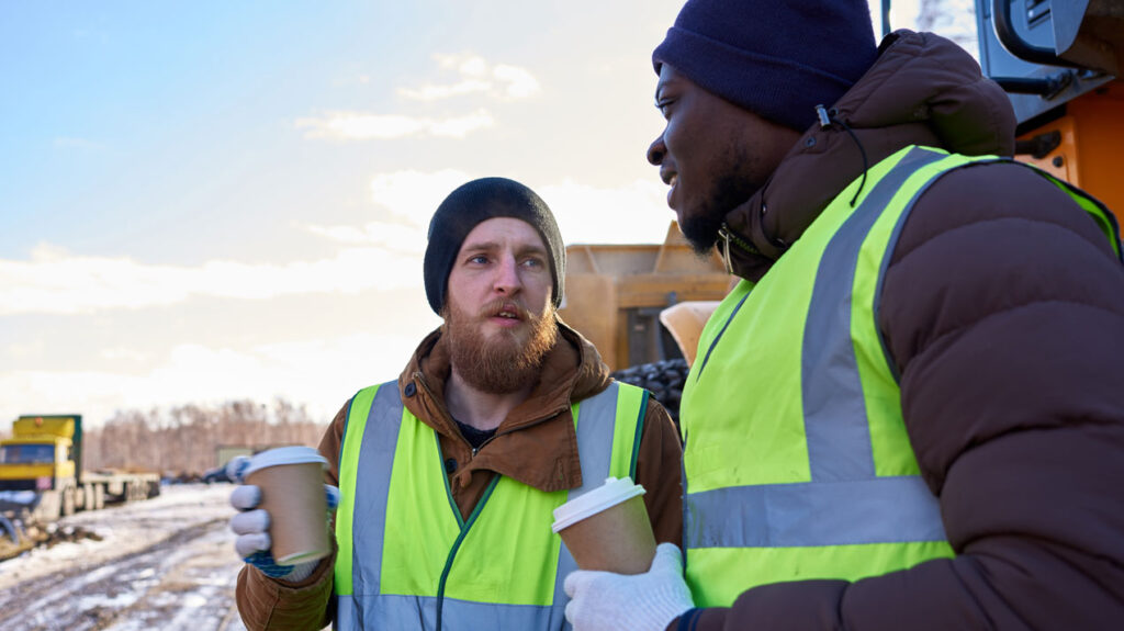 two men holding coffees at worksite